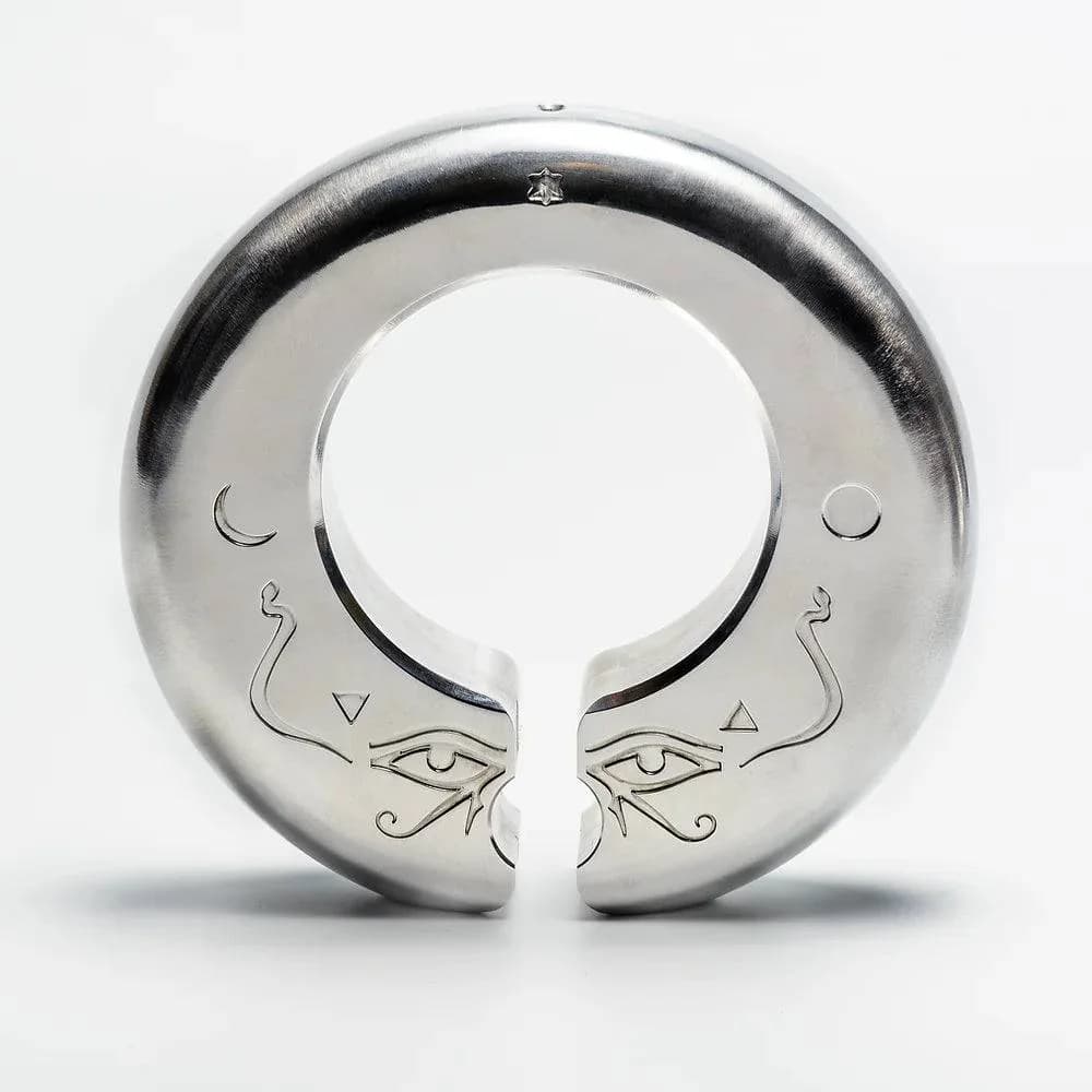 Sølvfarget, åpen ring med inngraverte symboler, sett skrått på lys bakgrunn