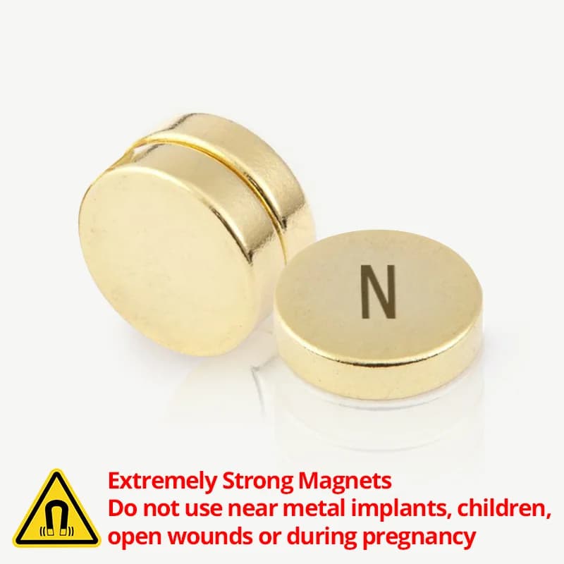 To gullfargede, runde magneter, den ene merket «N», med en advarsel om sterke magneter