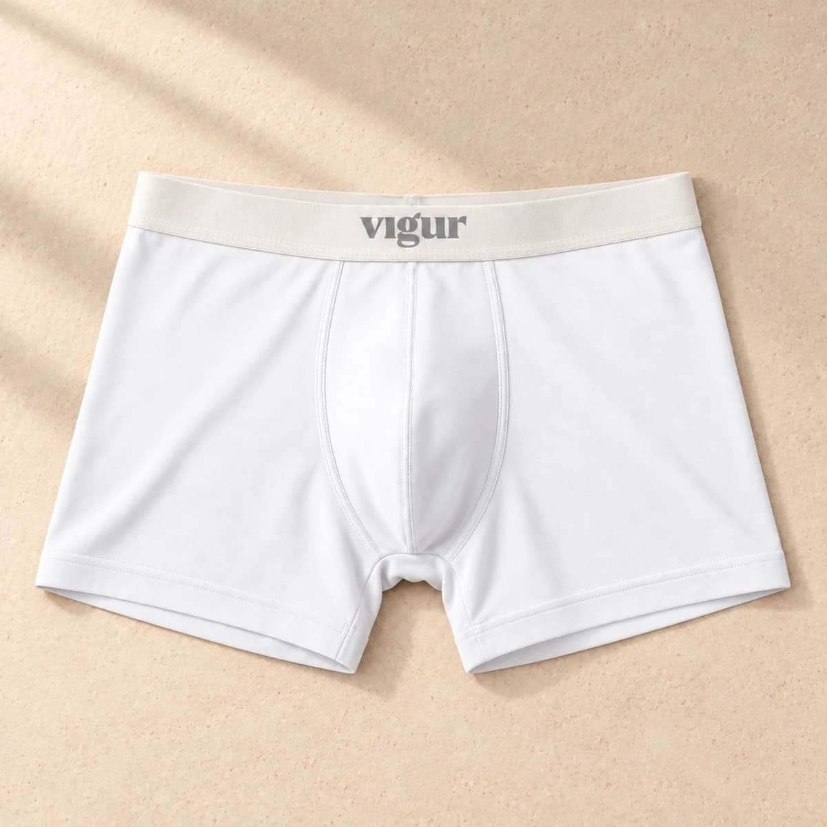 Lyse tettsittende boxershorts med lys linning merket Vigur, sett forfra på beige bakgrunn