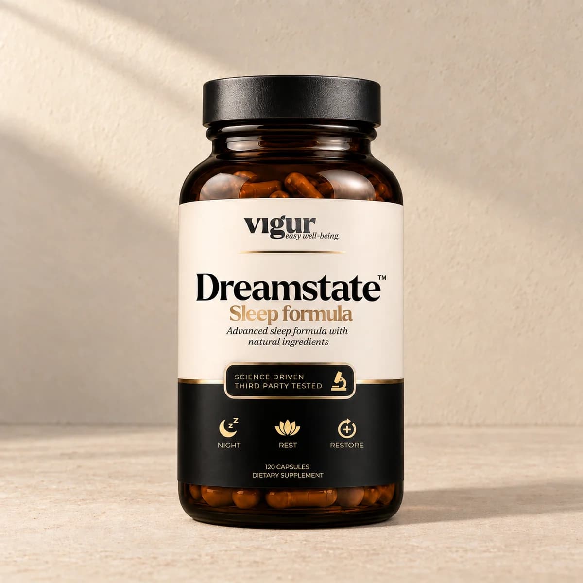 Mørk brun glassboks med svart lokk og lys etikett merket Vigur og «Dreamstate Sleep formula» på beige bakgrunn