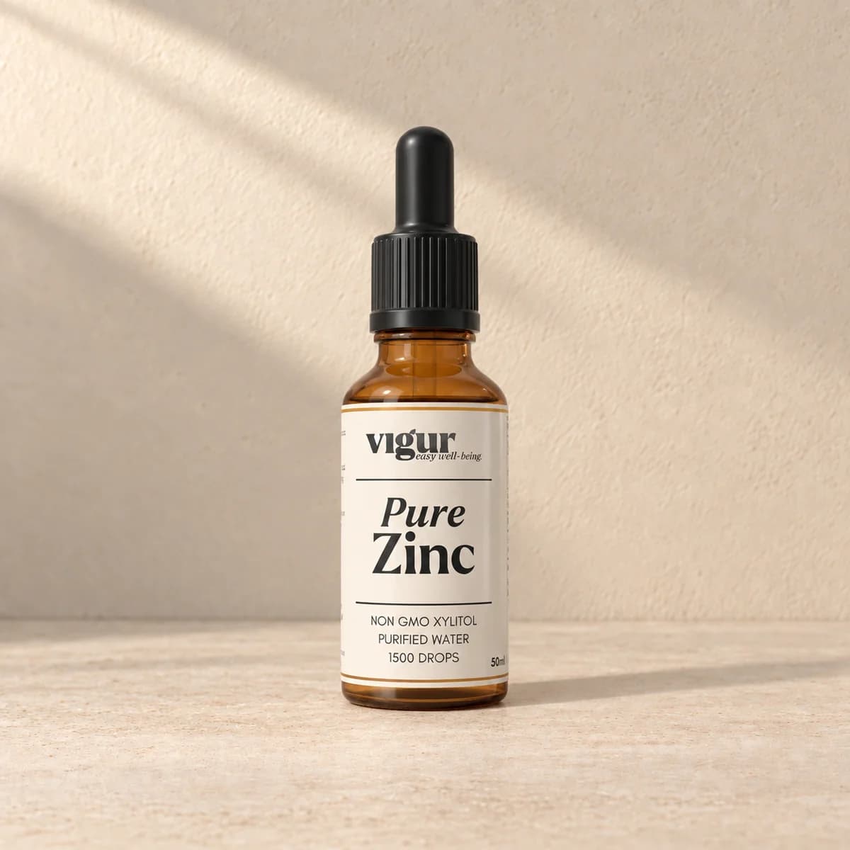 Liten brun glassflaske med pipettelokk og lys etikett merket Vigur og «Pure Zinc» på beige bakgrunn