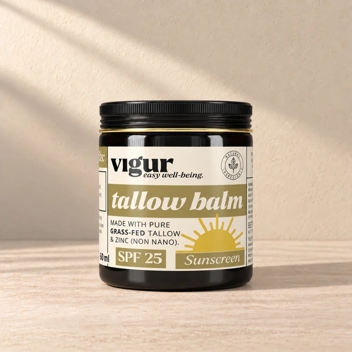 Svart boks med gul og lys etikett merket Vigur og «Tallow balm SPF 25 Sunscreen» på beige bakgrunn