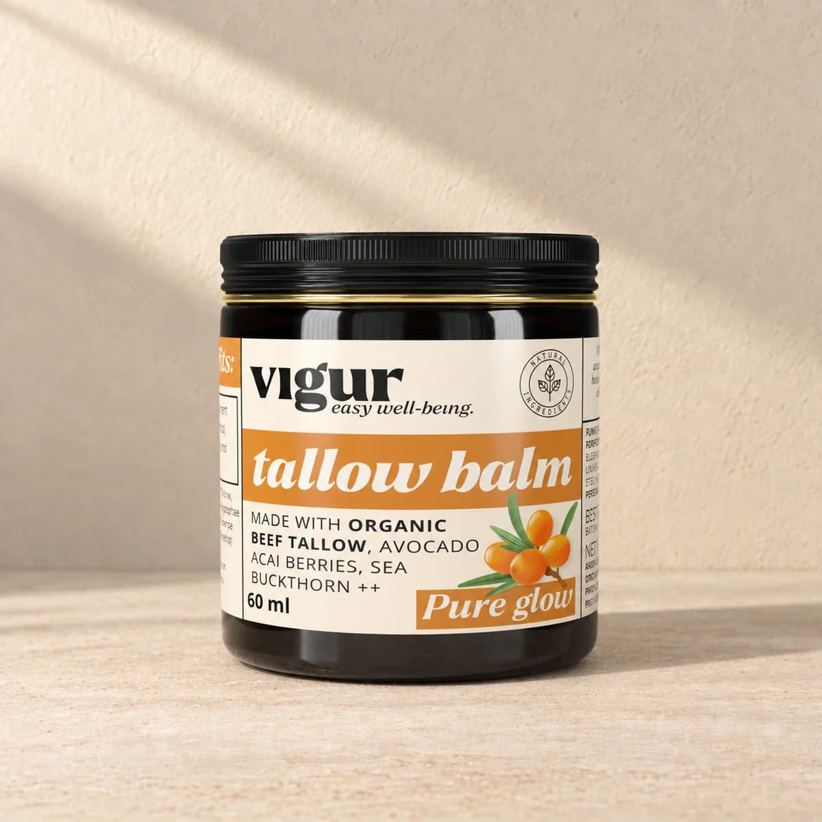 Svart boks med oransje og lys etikett merket Vigur og «Tallow balm Pure glow» på beige bakgrunn