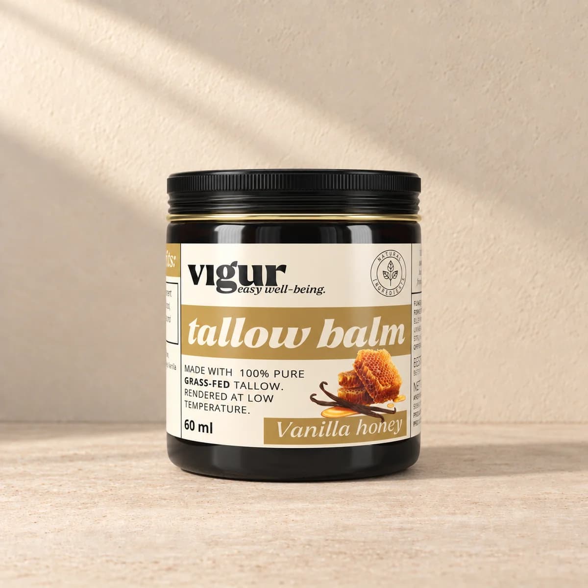 Svart-gul boks med lys etikett merket Vigur og «Tallow balm Vanilla Honey» på beige bakgrunn