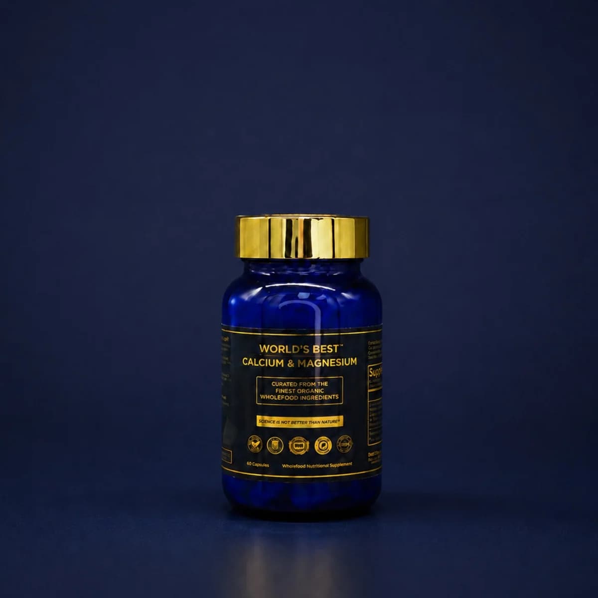 Blå glassflaske med gullkork og svart etikett med gullskrift: World's Best Calcium-Magnesium, mot mørkeblå bakgrunn